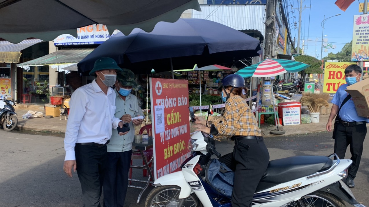 Lực lượng chức năng huyện kiểm tra thân nhiệt và yêu cầu người dân quét mã Bluezone khi vào chợ Bù Đăng, thị trấn Đức Phong, huyện Bù Đăng